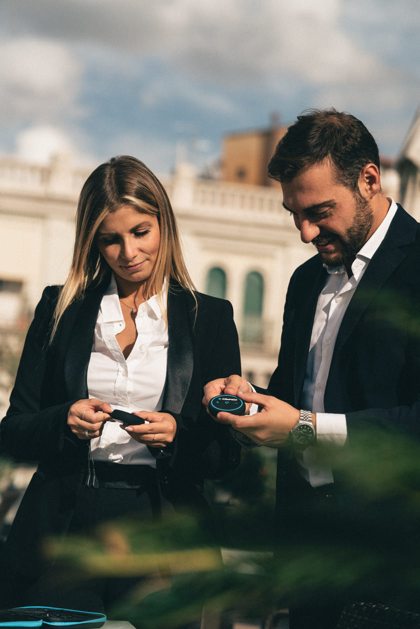 A man and a woman taking a look at the Compex Mini EMS muscle stimulator