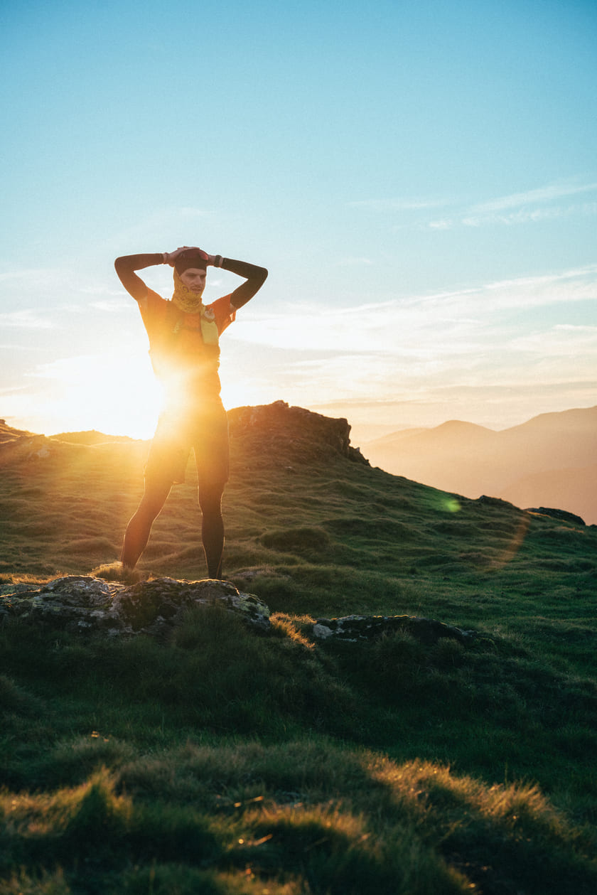 A man standing on a mountain with his hands on his head