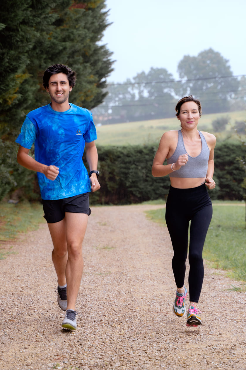 A man and a woman running on a gravel path