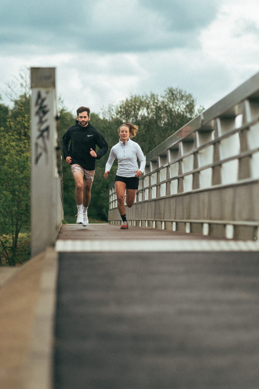A man and a woman running across a bridge