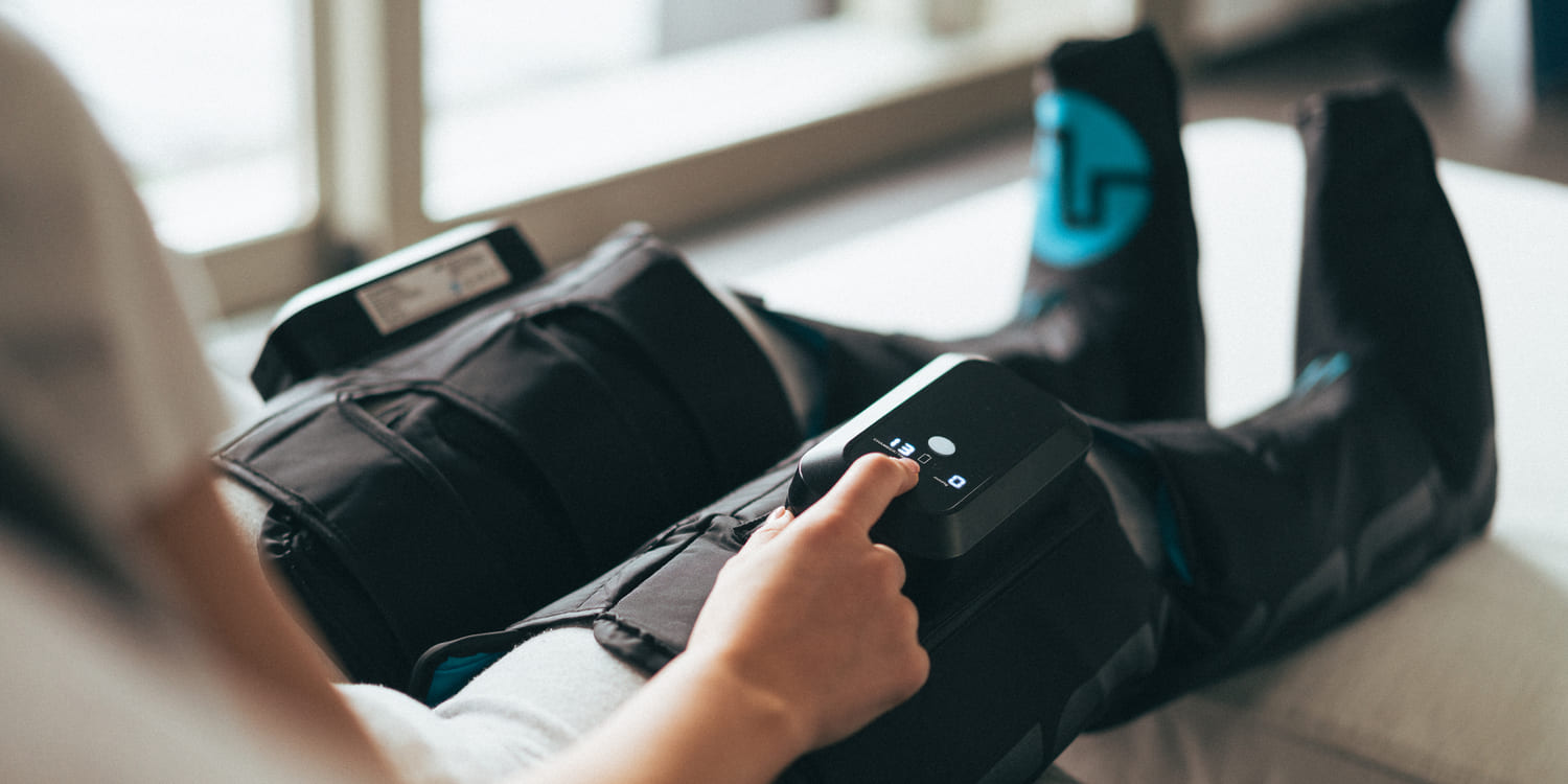 A woman turning on the Compex Ayre wireless compression boots
