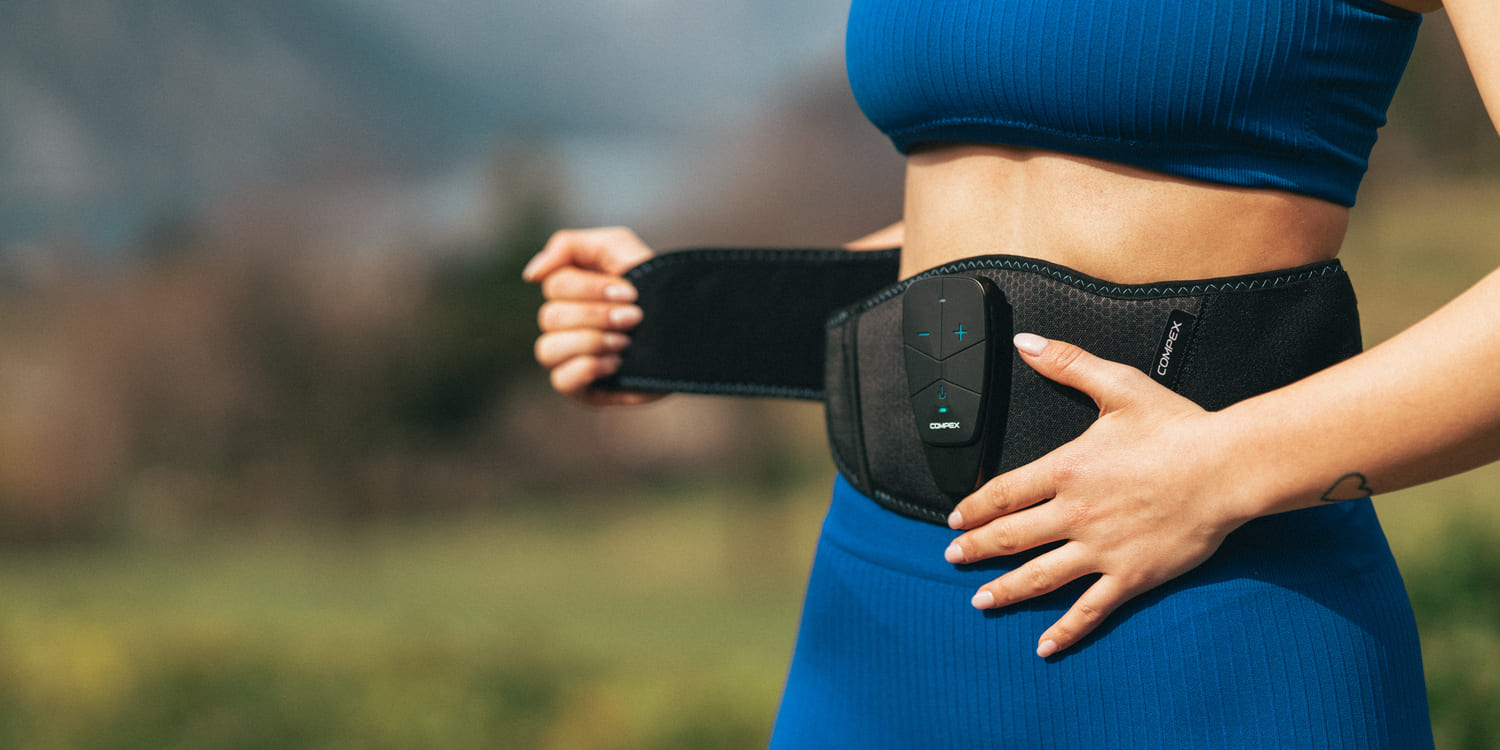 A woman putting on the Compex Corebelt EMS muscle stimulator belt