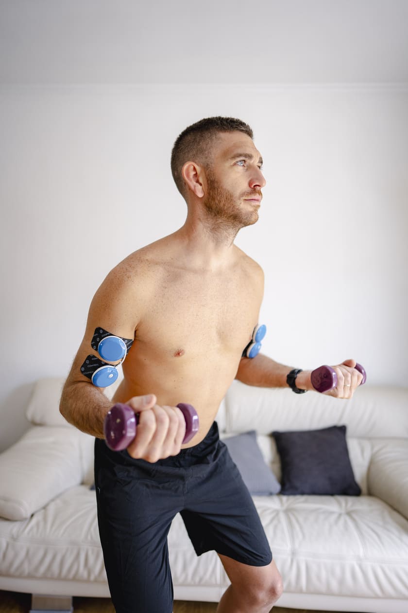 A man working on his biceps using the Compex FIT 5.0 EMS muscle stimulator
