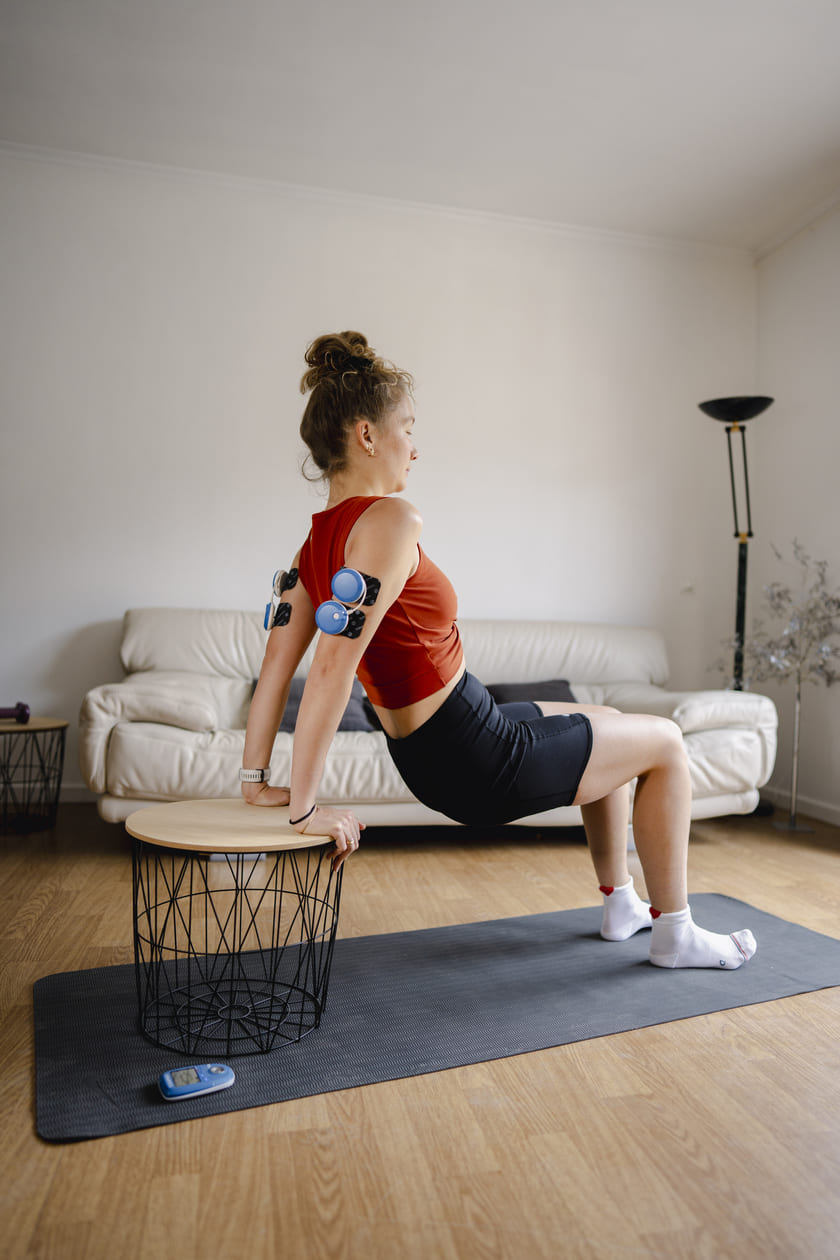 A woman working on her triceps using the Compex FIT 5.0 EMS muscle stimulator
