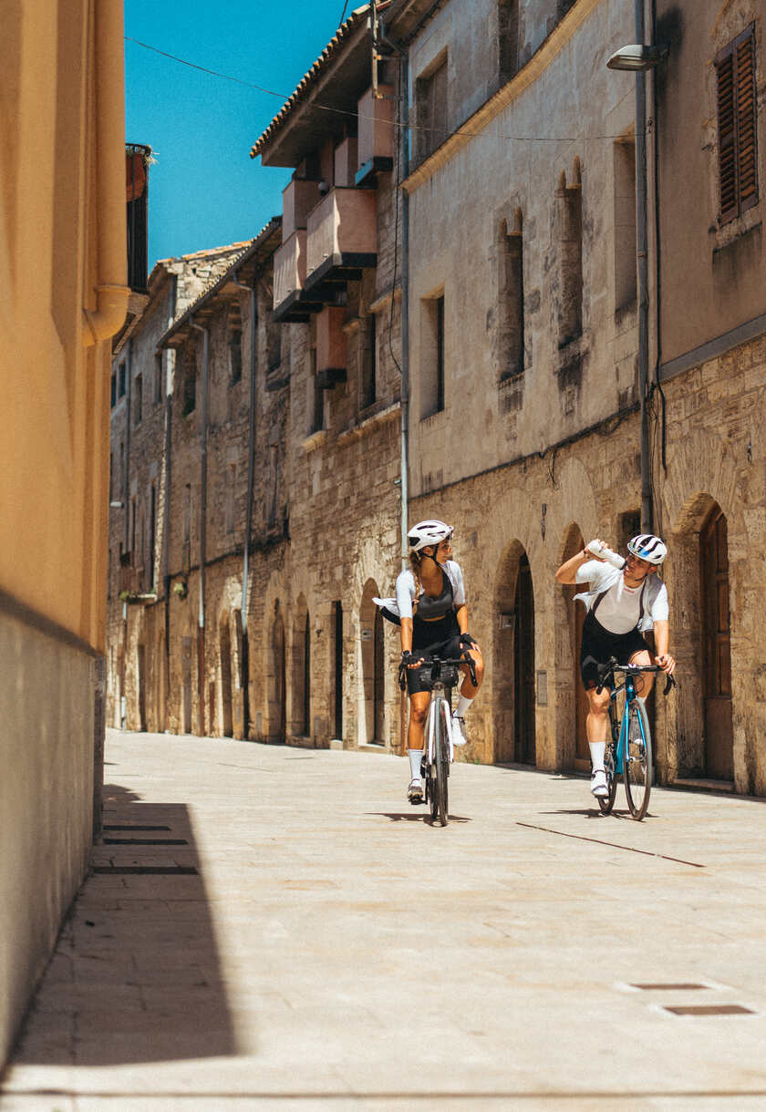 A couple cycling through a village centre