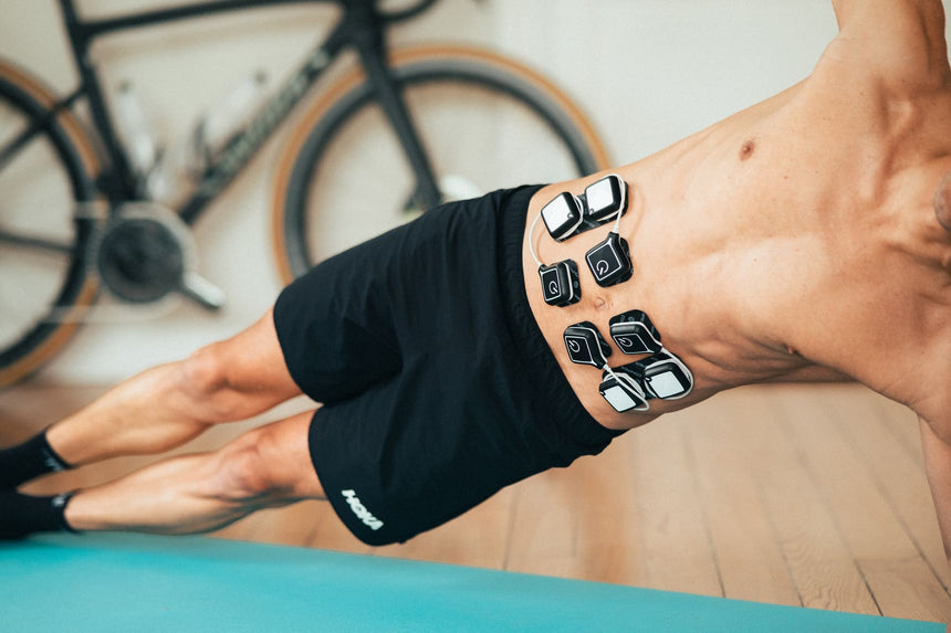 A man doing a side plank, using the Compex Ultimate Pro EMS device to tone his abdominal muscles