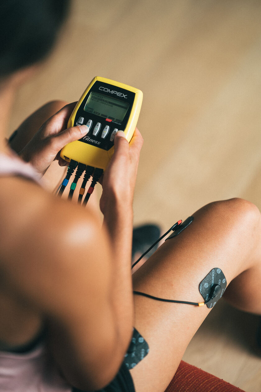 A woman using the Compex Fitness EMS muscle stimulator on her quads
