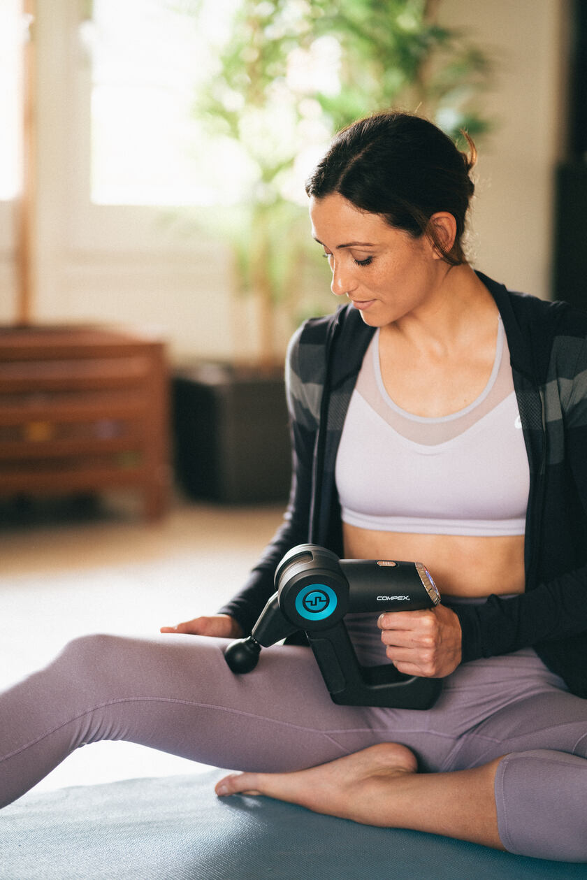 A woman massaging her quads using the Compex Fixx 2.0