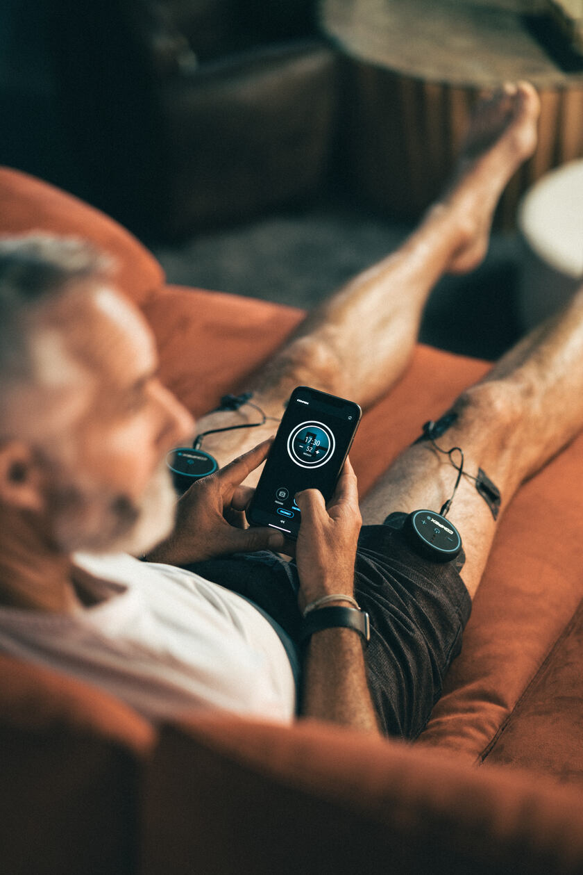 A man using the Compex Mini on his quads