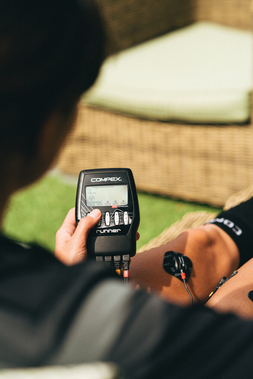 A woman using the Compex Runner EMS muscle stimulator on her quads