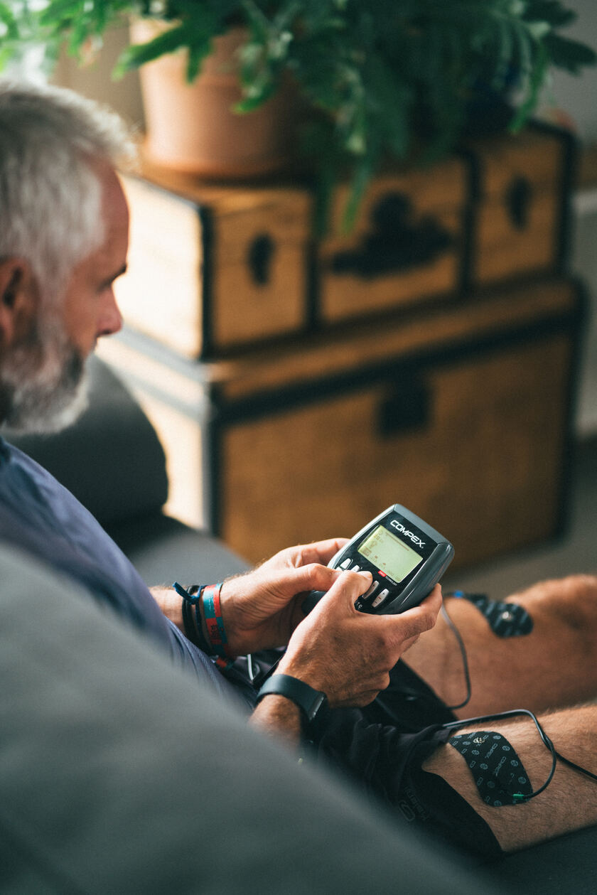 A man using the Compex Sport Elite EMS muscle stimulator on his quads