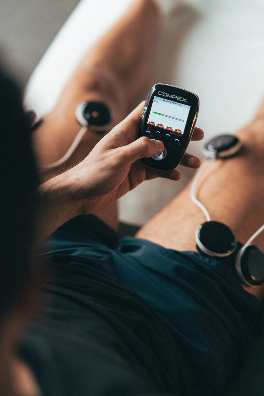 A man using the Compex SP 6.0 EMS muscle stimulator on his quads