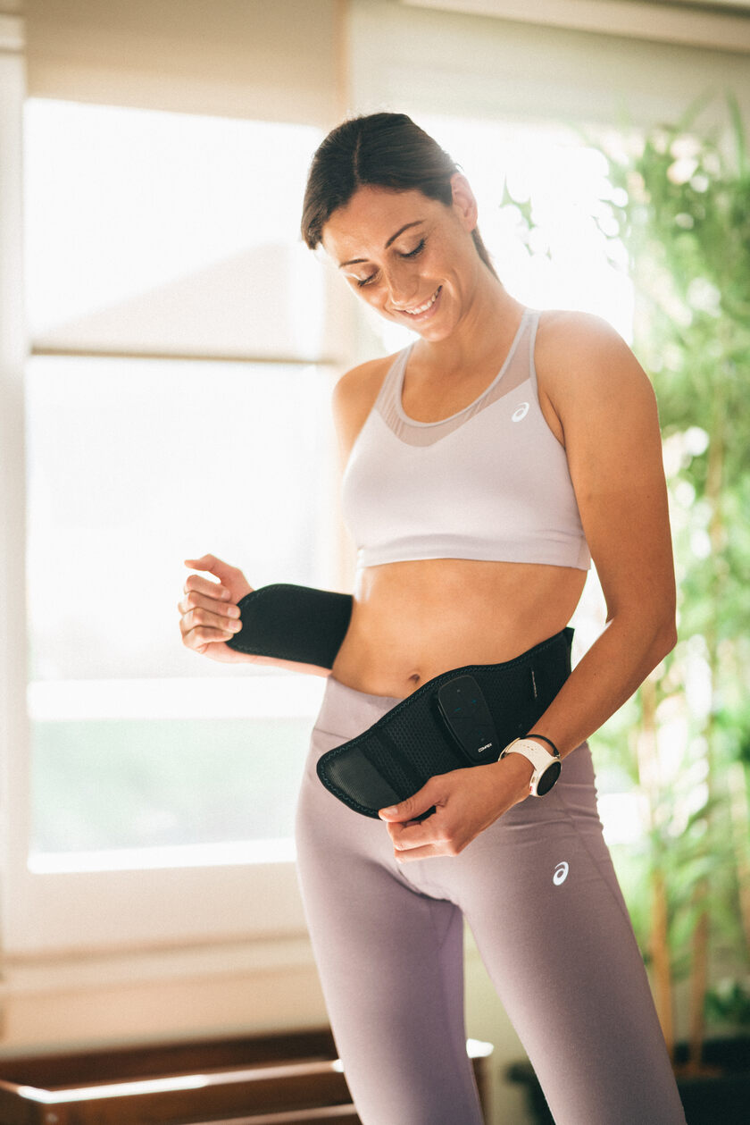 A woman putting the Compex Corebelt on