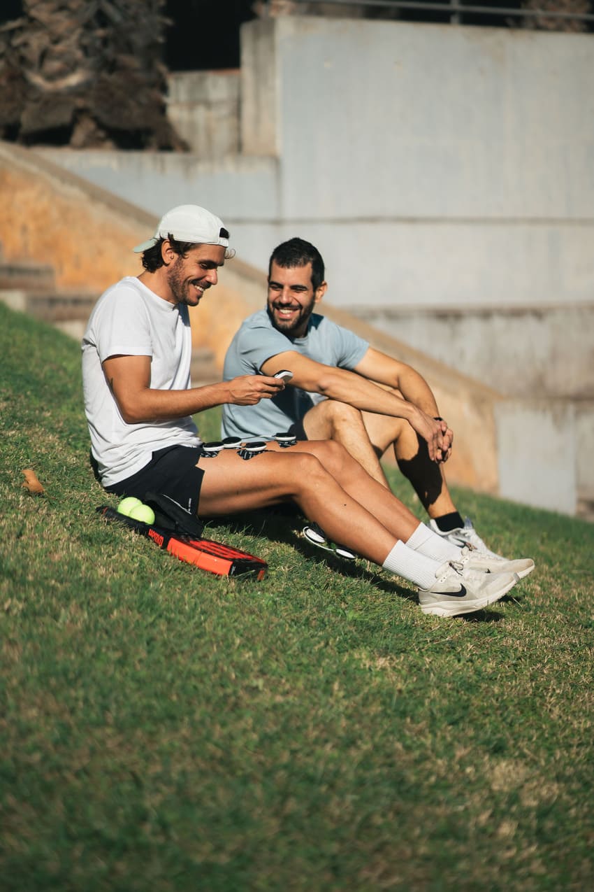 A padel player and his friend using the Compex SP 8.0 EMS muscle stimulator on his quad and calf muscles