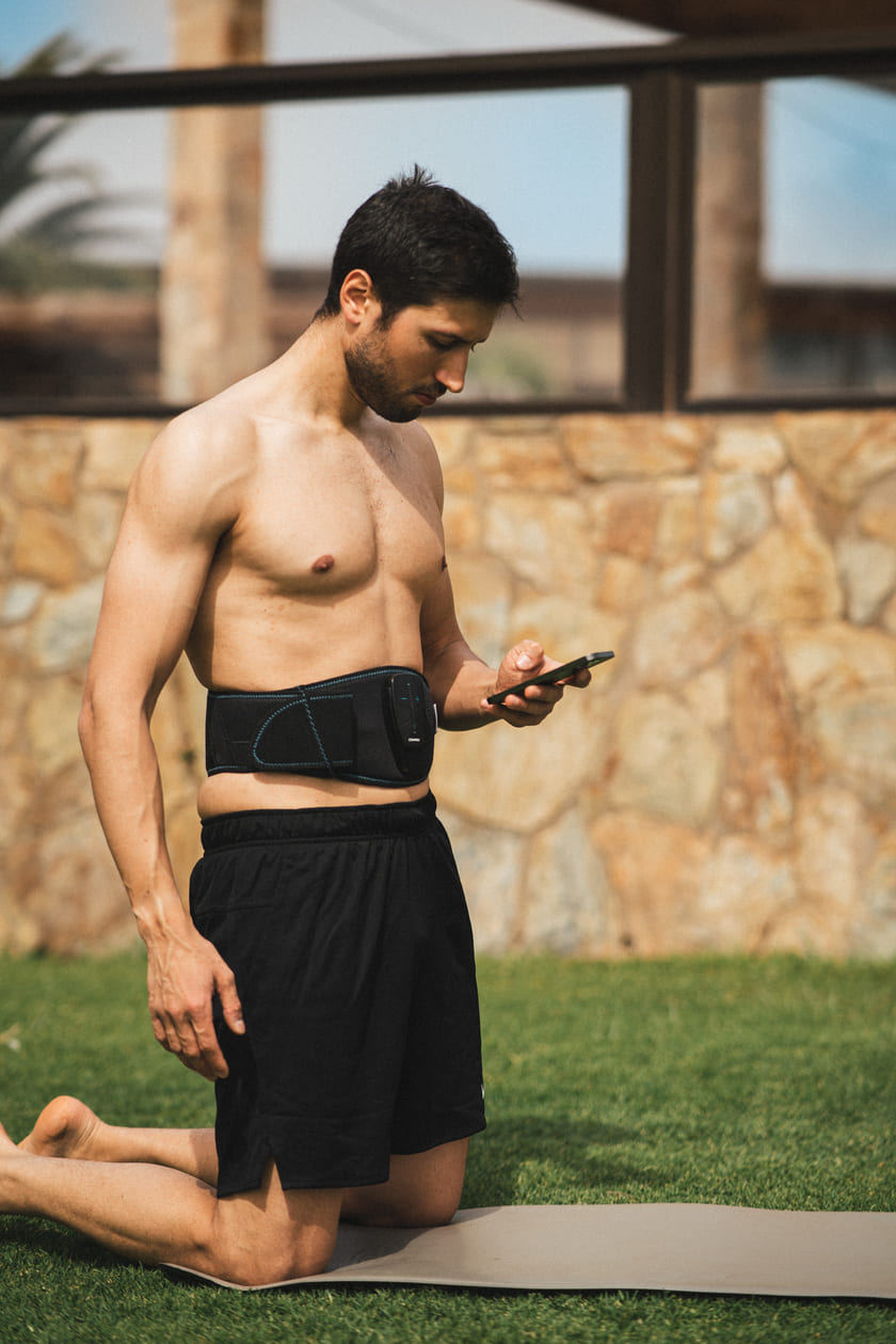 A man doing an ab workout using the Compex Corebelt EMS muscle stimulation belt