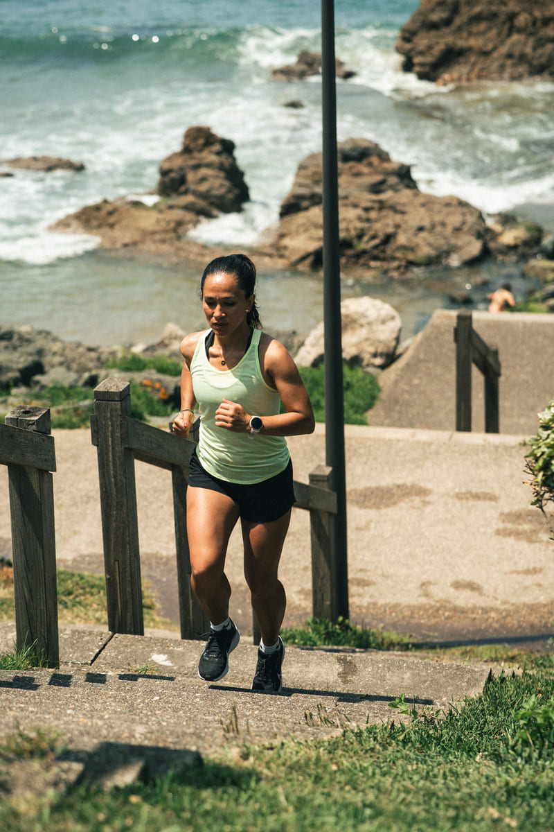 A woman running up some stairs near the ocean