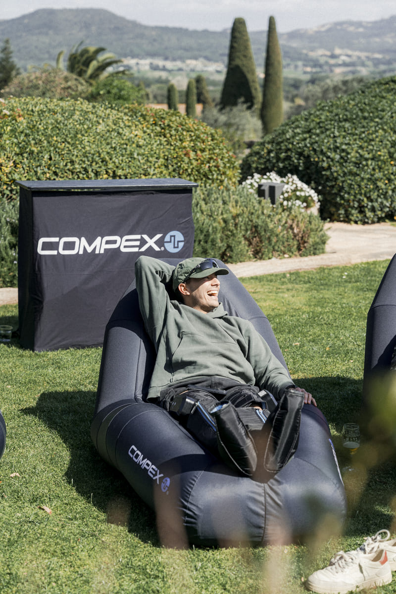 A man relaxing outside using the Compex Ayre wireless compression boots
