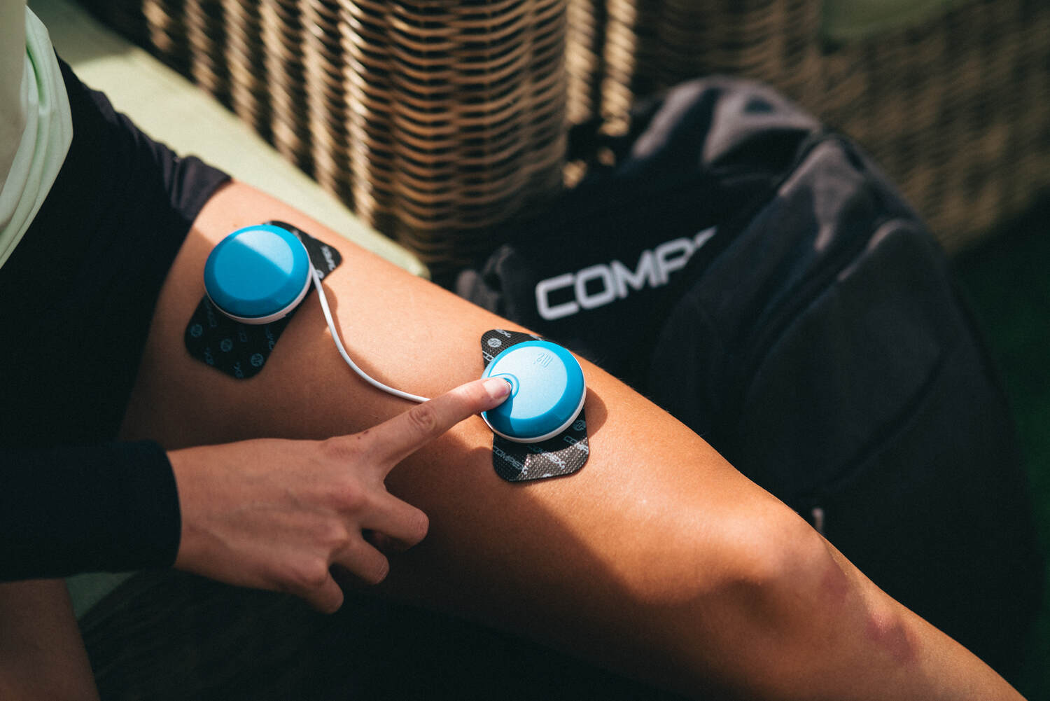 A woman using a wireless Compex EMS muscle stimulator