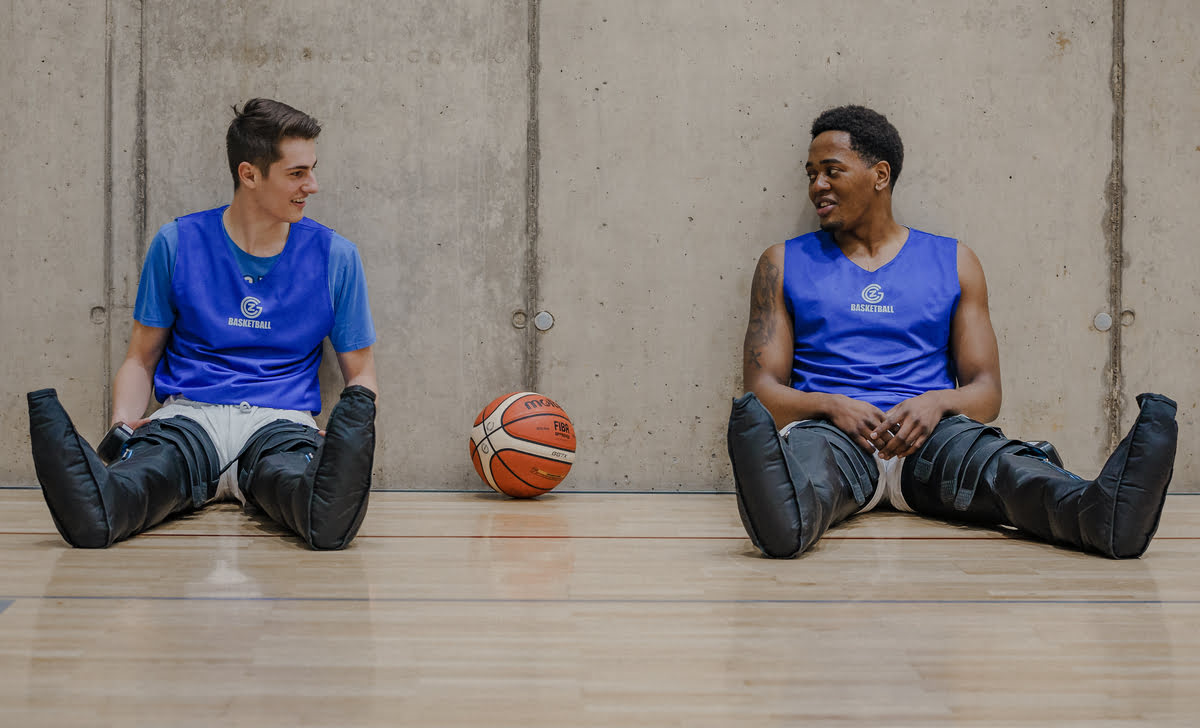 Zwei Basketballspieler erholen sich mit Compex Ayre Kompressionsschuhen