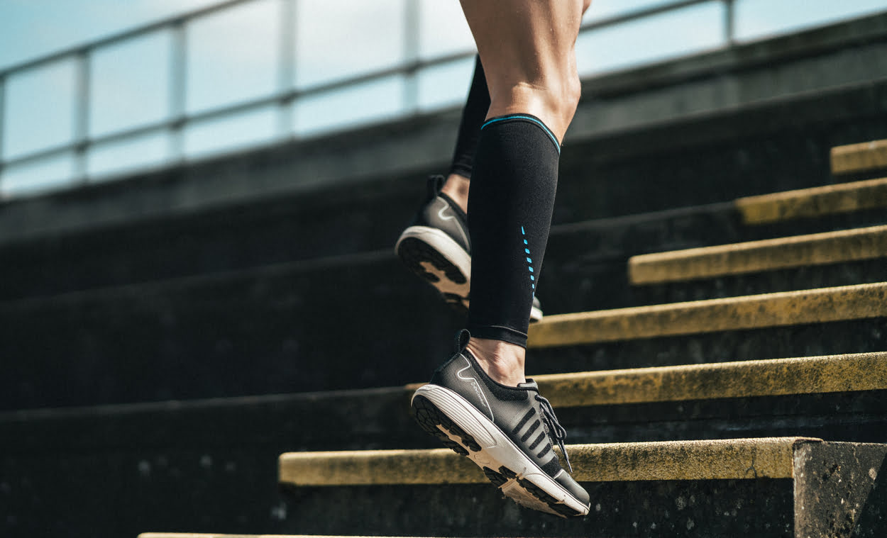 Man running up steps wearing Compex Activ' Calf Sleeves