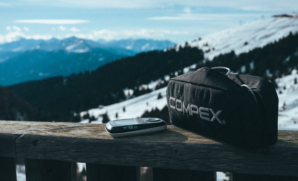 The Compex SP 8.0 muscle stimulator in front of snowy mountains
