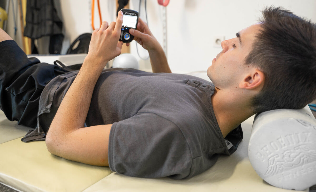 An athlete treating pain with the Compex SP 8.0 muscle stimulator