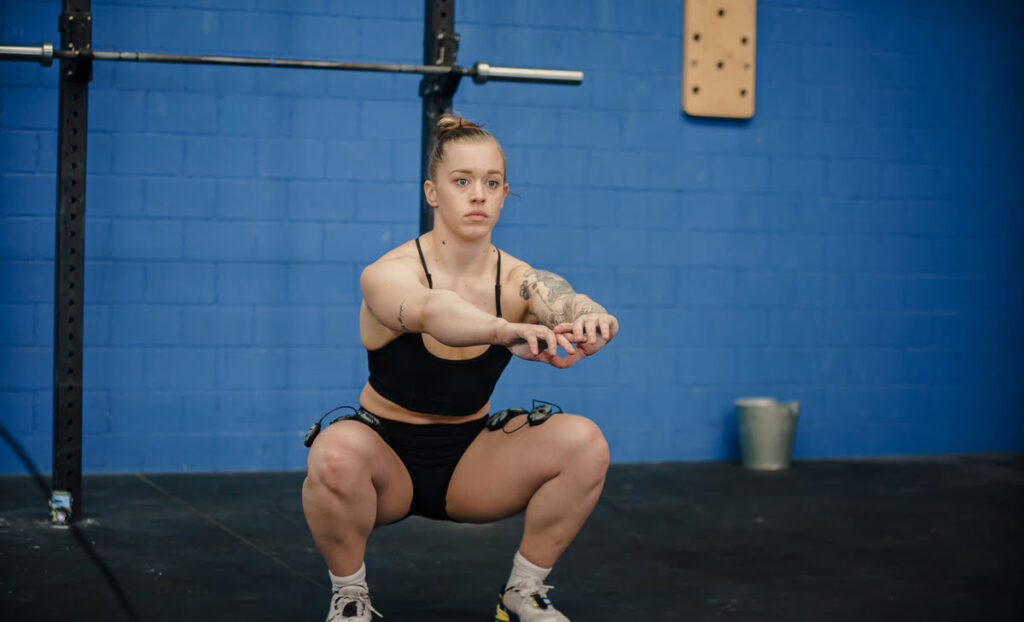 A female athlete squatting using the Compex SP 8.0 WOD Edition