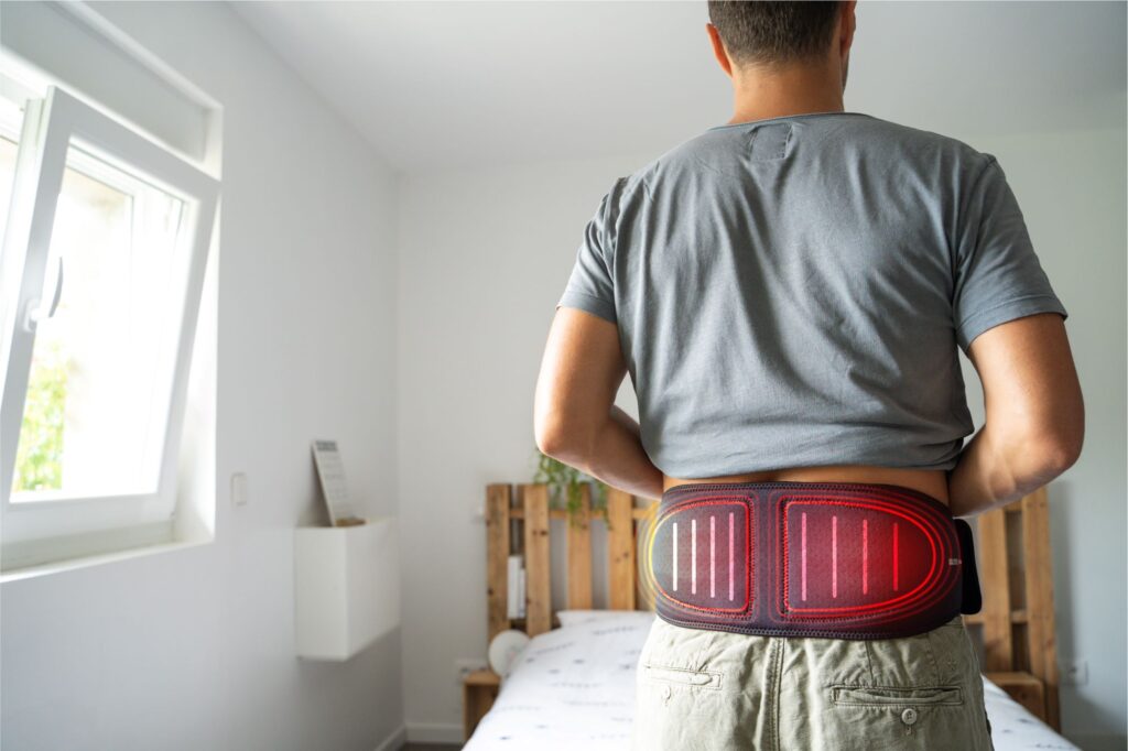 A man treating back pain using the Compex Back Wrap
