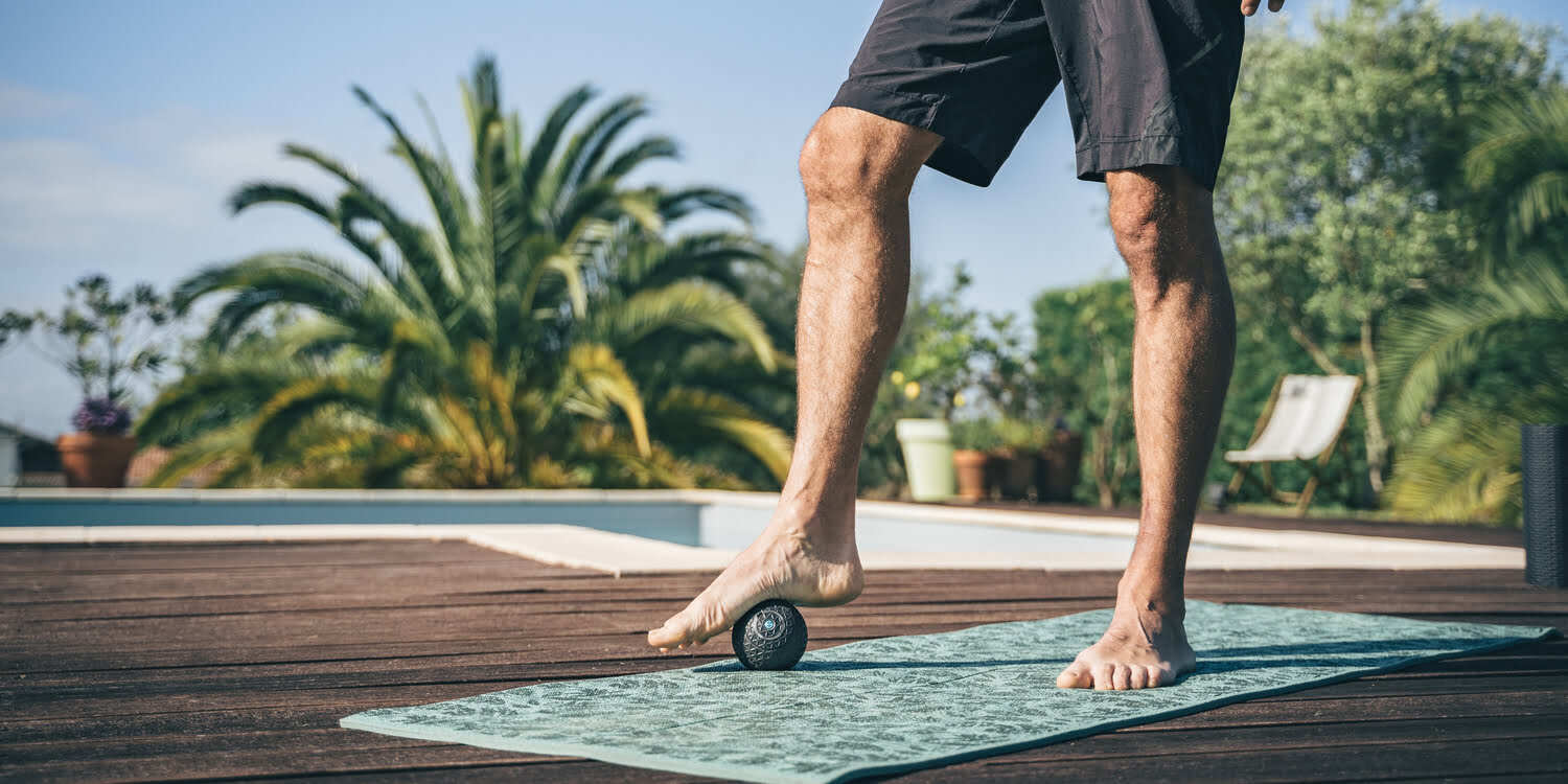 UN HOMME SE MASSANT LE PIED AVEC LA Compex Molecule