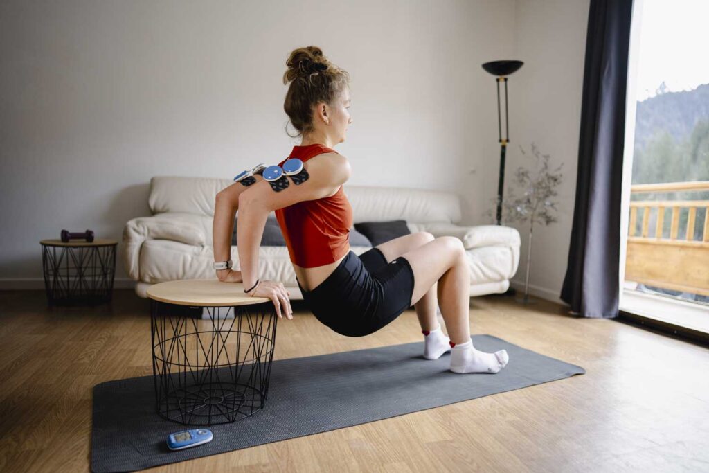 A woman doing tricep dips using the Compex FIT 5.0 muscle stimulator