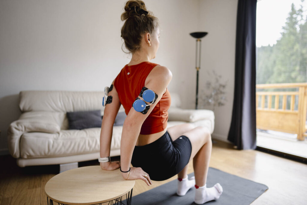 A woman doing tricep dips using the Compex FIT 5.0 muscle stimulator