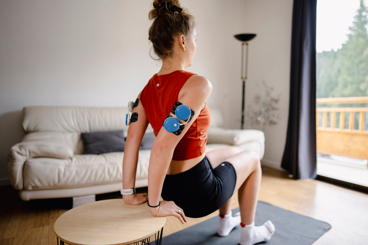 A woman exercising her arms using the Compex FIT 5.0 muscle stimulator