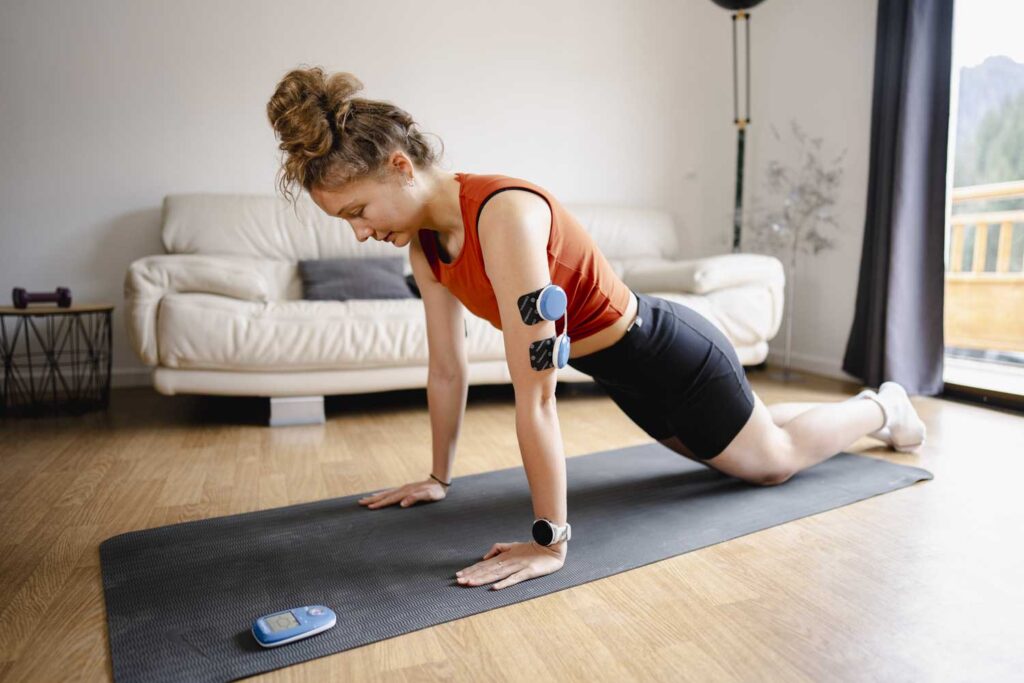 A woman doing push ups using the Compex FIT 5.0 muscle stimulator