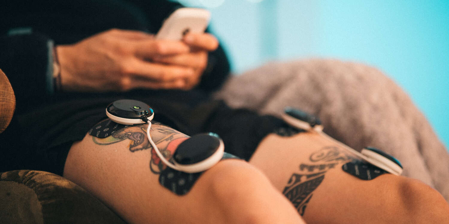 A man treating his DOMS using a Compex electrostimulator