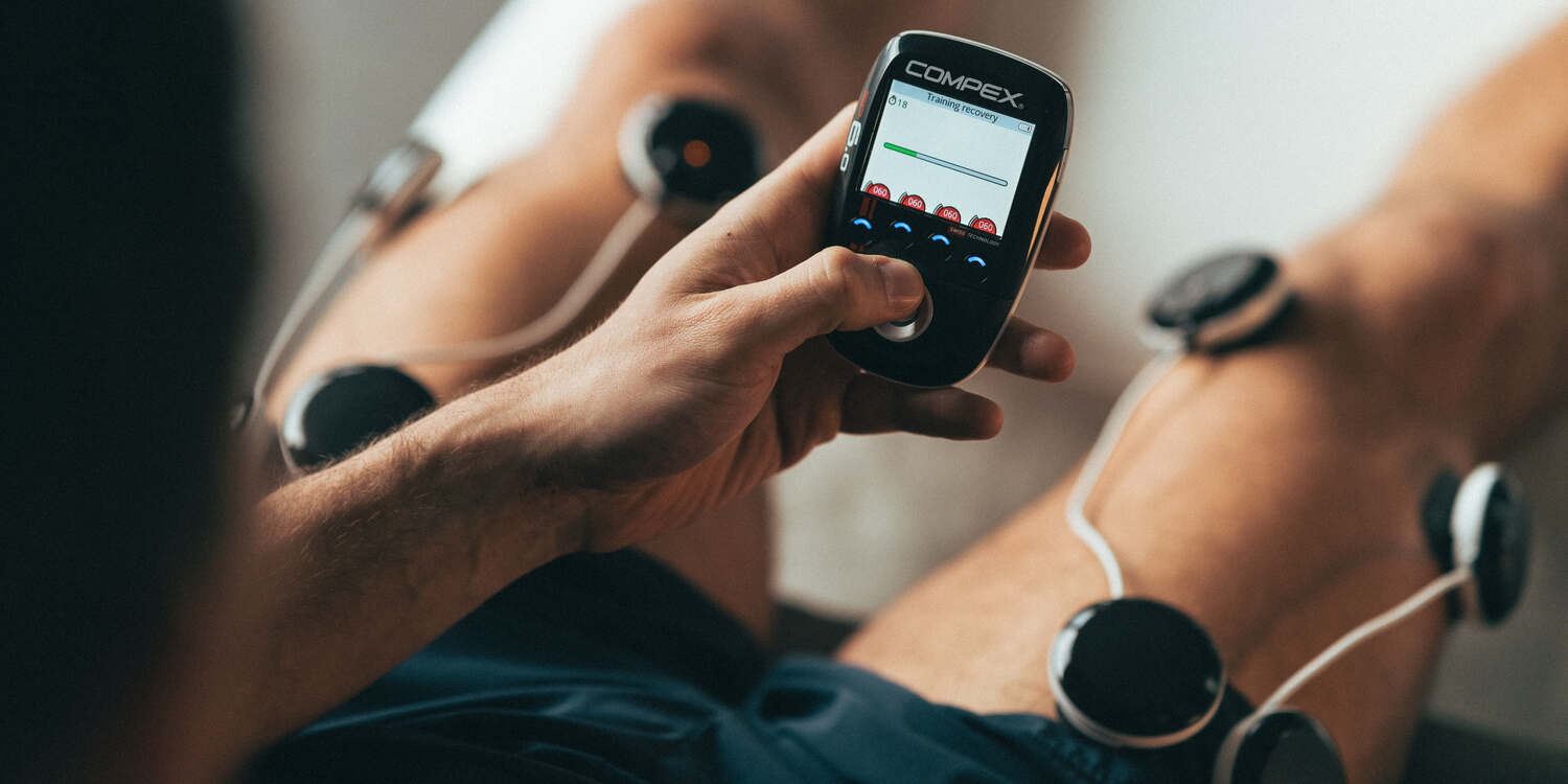 A man treating his DOMS using a Compex electrostimulator