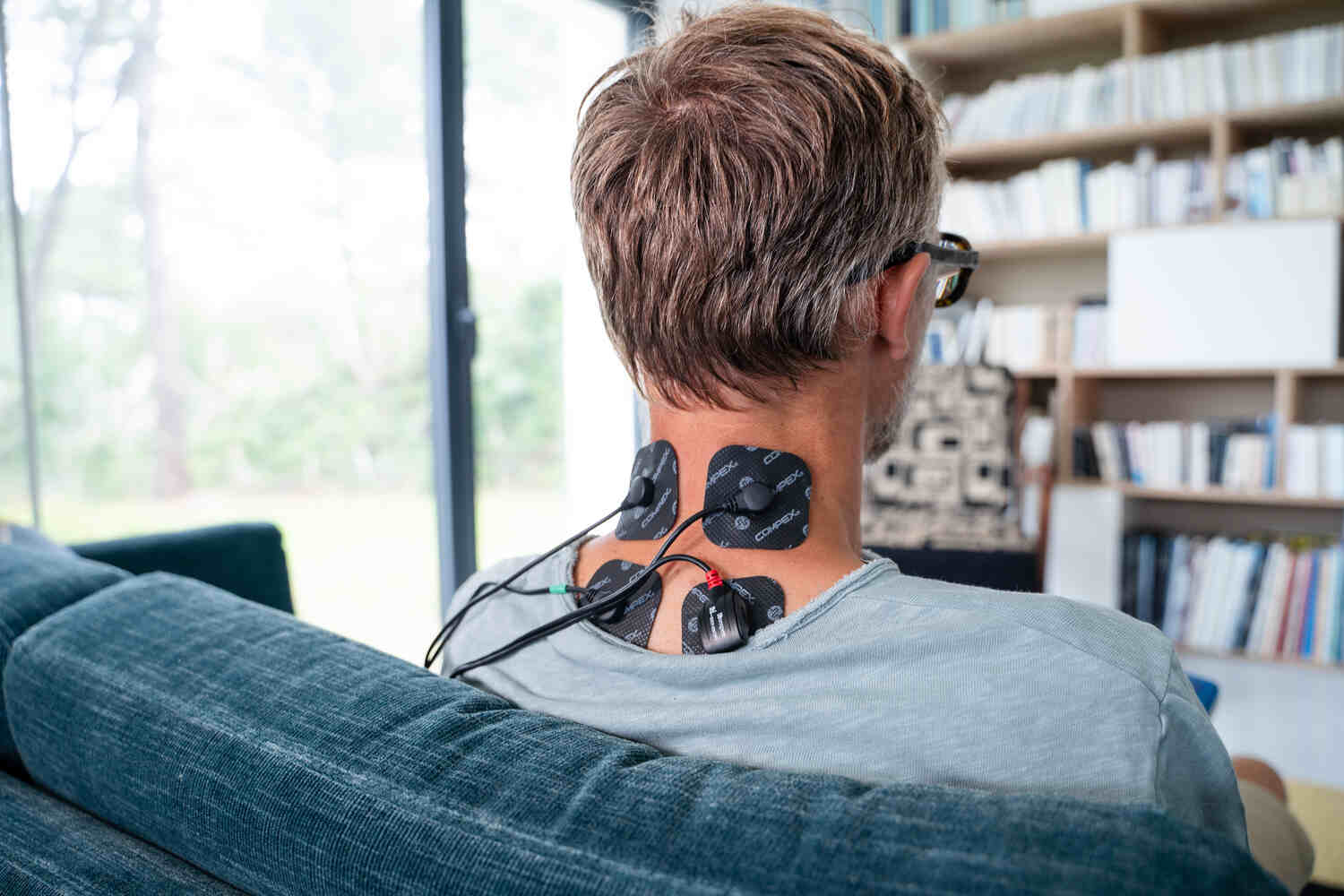 A man using electrostimulation with a Compex SP 4.0 to relax his neck muscles