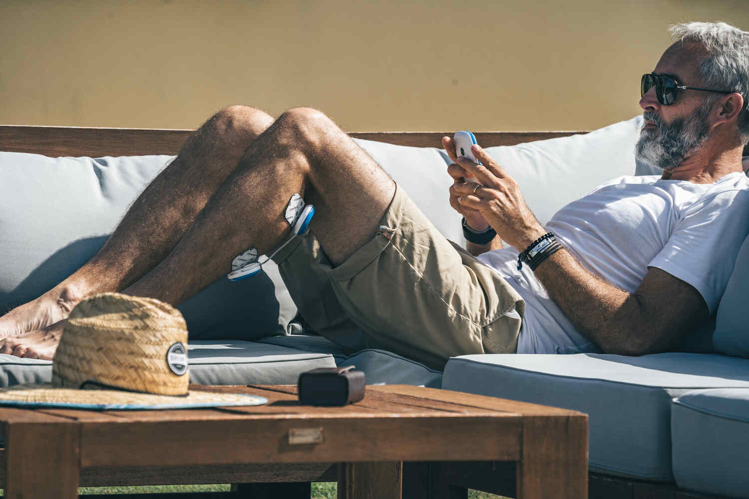 A man relaxing in the sun using the Compex FIT 5.0 muscle stimulator
