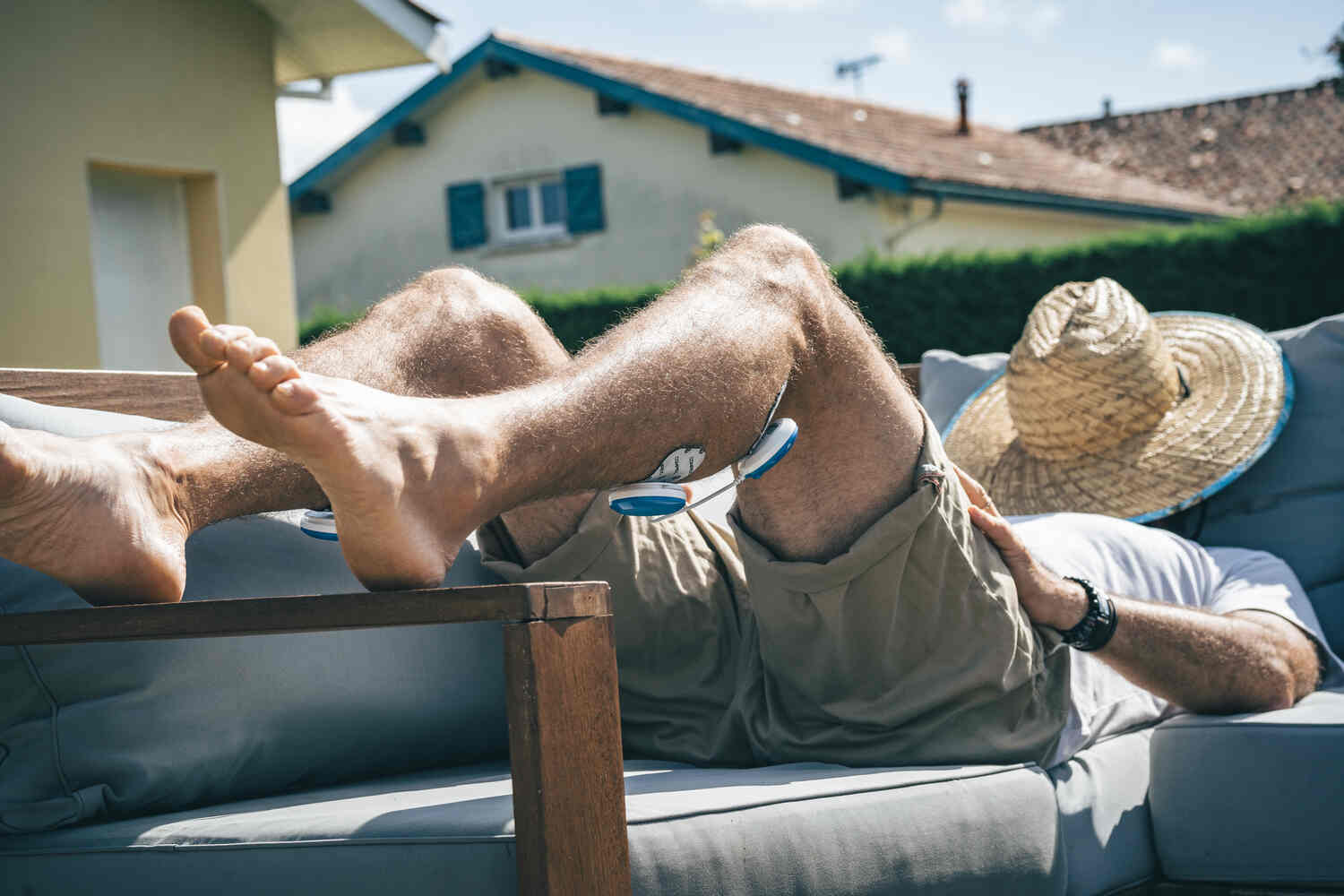 A man relaxing in the sun using the Compex FIT 5.0 muscle stimulator