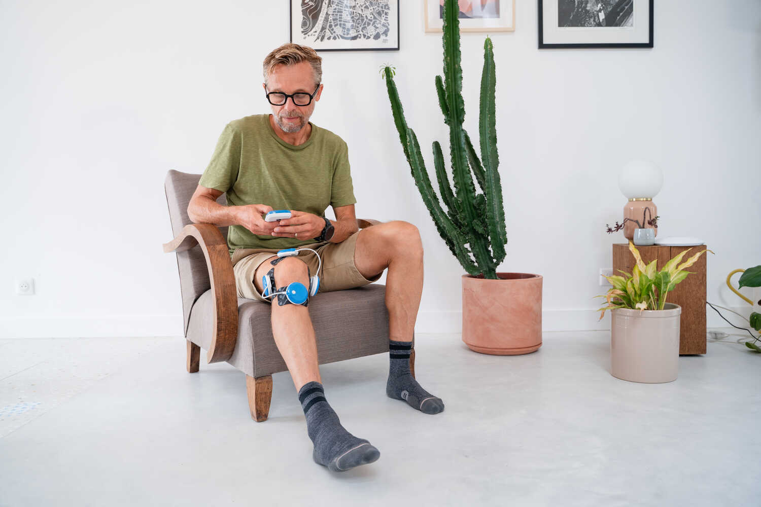A man using the Compex FIT 5.0 muscle stimulator to treat joint pain in his knee