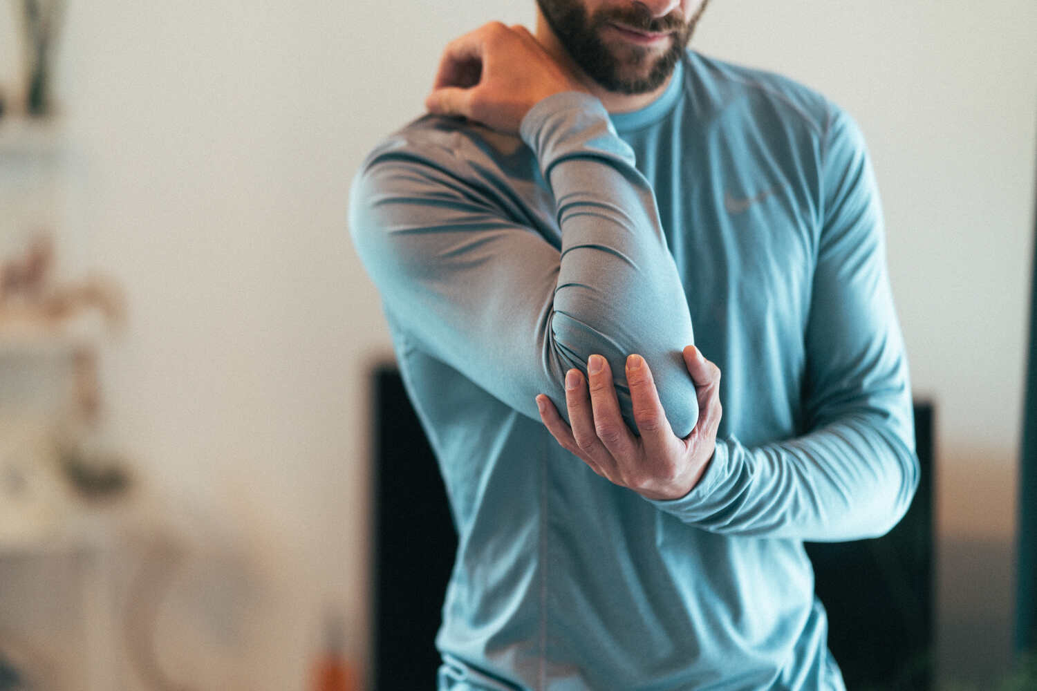 A man holding his elbow in discomfort due to joint pain