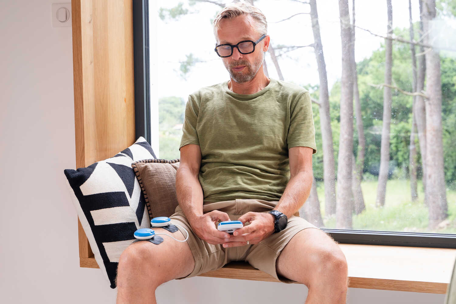 A man using a Compex FIT 5.0 electrostimulator on his quad muscle