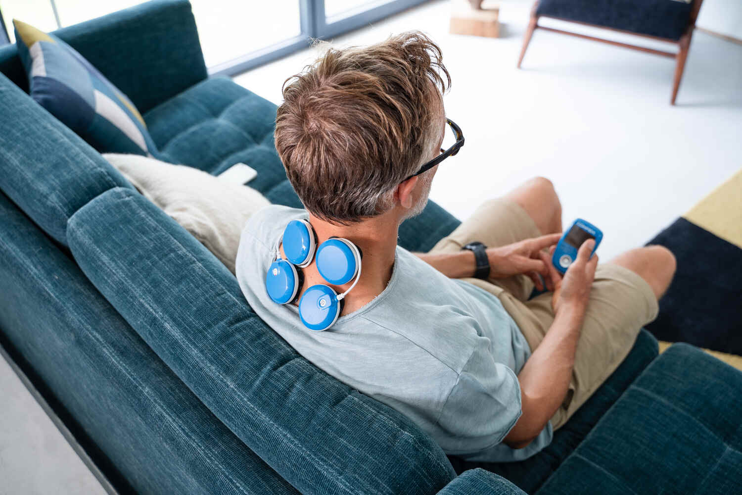 A man treating his neck pain the Compex FIT 5.0 electrostimulator