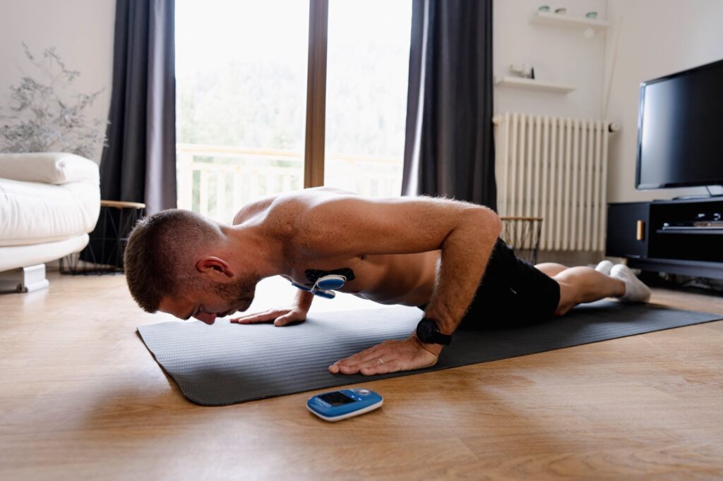 Een man doet push-ups met de Compex FIT 5.0 spierstimulator