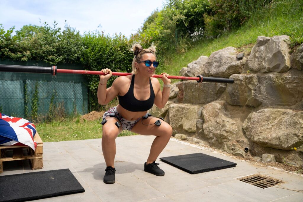 een vrouw die squats doet met een elektrostimulator