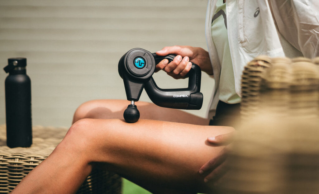 A woman massaging her quads with Compex Fixx 1.0, practicing self-care