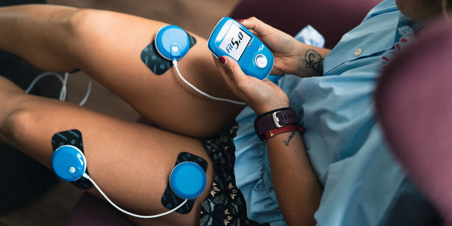 A woman toning her thighs using the Compex FIT 5.0 muscle stimulator